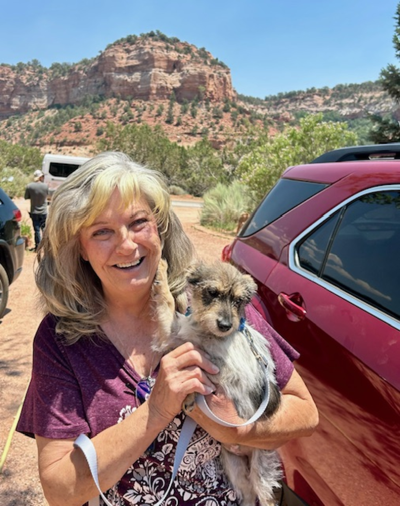 Freya the puppy with her smiling adopter beside a vehicle